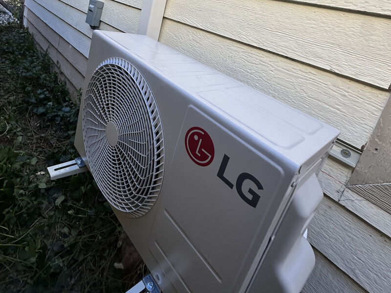 Outdoor condensing unit mounted on brackets against a building wall